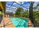 Backyard pool with a screened-in enclosure, chairs and lounge area, and lush landscaping at 8808 Macapa Dr, Kissimmee, FL 34747
