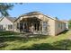 Back exterior view of house with a screened patio and green grass at 9723 Pecky Cypress Way, Orlando, FL 32836