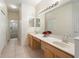 Bathroom featuring a double vanity, tiled floors, and a well-lit mirror, with hallway view at 9723 Pecky Cypress Way, Orlando, FL 32836