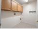 Functional laundry room with tile flooring, storage cabinets, and hook rack at 9723 Pecky Cypress Way, Orlando, FL 32836