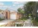 Tan single-story home featuring an attached garage and mature landscaping at 1040 Hamlet Dr, Maitland, FL 32751