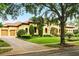 Charming Mediterranean home featuring lush green lawn, mature trees and a brick driveway at 11055 Ullswater Ln, Windermere, FL 34786