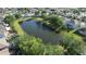 Aerial view of a large community pond surrounded by trees, pools, and well-maintained homes at 13520 Meadow Bay Loop, Orlando, FL 32824