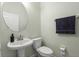Well-lit half bathroom with a pedestal sink, toilet, and round mirror, ideal for guests at 1530 Tally Cir, Oviedo, FL 32765