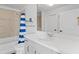 Bright bathroom featuring a white vanity, white toilet, and shower with blue striped curtain at 155 S Court Ave # 1202, Orlando, FL 32801