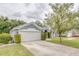 Home featuring an attached two car garage, mature landscaping, and large driveway at 157 Long Pine Dr, Deltona, FL 32725