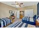 Bright bedroom showcasing two striped beds and a ceiling fan, offering comfort and style at 200 Valencia Ridge Dr, Auburndale, FL 33823