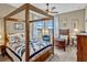 Cozy main bedroom boasts a four poster bed, accent chair and water views at 200 Valencia Ridge Dr, Auburndale, FL 33823
