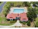 An aerial view of a community pool with clear blue water and a red roofed clubhouse surrounded by lounge chairs and lush landscaping at 200 Valencia Ridge Dr, Auburndale, FL 33823