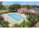 An aerial view of a community pool with a clubhouse, surrounded by palm trees, lush landscaping, and a black metal fence at 200 Valencia Ridge Dr, Auburndale, FL 33823