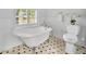 Bright bathroom features a vintage clawfoot tub, tile floor, and decorative wainscoting at 2004 E Marks St, Orlando, FL 32803