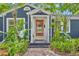 Inviting front entrance with a vibrant orange door, complemented by lush tropical landscaping at 2004 E Marks St, Orlando, FL 32803