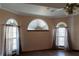 Bright bedroom featuring three unique arched windows and light-filtering curtains at 20951 County Road 561, Clermont, FL 34715
