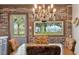 A cozy dining room with brick walls, chandelier lighting, and scenic outdoor views through large windows at 2519 Gabriel Rd, Fort Meade, FL 33841