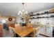 Open kitchen with a chandelier, wooden shelves, stainless steel appliances, and floral upholstered chairs at 2519 Gabriel Rd, Fort Meade, FL 33841