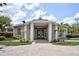 Community clubhouse entrance with brick pathway, columns, and manicured landscaping under a cloudy sky at 2626 Greenwillow Dr, Orlando, FL 32825