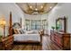 Serene main bedroom features beautiful hardwood floors, large windows, and refined wooden furniture at 2626 Greenwillow Dr, Orlando, FL 32825