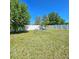 Spacious backyard featuring green grass and trees under a clear blue sky at 3301 Bethpage Loop, Mount Dora, FL 32757