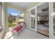 A cozy screened patio with a red chaise lounge, offering views of the lush backyard and access to the living area at 336 Sunset Oaks Rd, Winter Garden, FL 34787