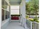 Relaxing porch swing adorned with cozy red pillows, framed by white railings and columns for a serene outdoor space at 336 Sunset Oaks Rd, Winter Garden, FL 34787