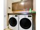 Laundry room features modern washer and dryer beneath upper storage cabinets and a countertop at 400 Shelby Ct, Apopka, FL 32712