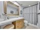 Bright bathroom featuring a framed mirror, vanity with a stool, and a shower with a decorative curtain at 401 Sanford Ave, Longwood, FL 32750
