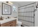 Modern bathroom features wood vanity, sleek fixtures, decorative mirror, and stylish shower curtain at 4636 Mesa Verde Dr, St Cloud, FL 34769