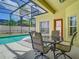 View of a screened-in patio with dining set overlooking a sparkling swimming pool and manicured backyard at 610 Carey Way, Orlando, FL 32825