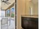 Bathroom vanity area with dark brown cabinets next to an outdoor patio with a table and chairs at 7618 Oakmoss Loop, Davenport, FL 33837