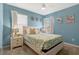 Bedroom with blue walls features a ceiling fan, windows with curtains, and decorative wall art at 7618 Oakmoss Loop, Davenport, FL 33837