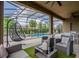 Covered patio with comfortable wicker seating, ceiling fans, and serene views of the pool and backyard at 7618 Oakmoss Loop, Davenport, FL 33837