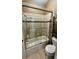 A bathroom featuring a tiled shower and glass door, accompanied by a standard toilet and storage rack at 7629 Chapelhill Dr, Orlando, FL 32819
