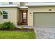 Close-up of a home's entrance with a red front door, a two-car garage, and manicured landscaping at 905 Ocean Course Ave, Davenport, FL 33896