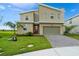 Contemporary two-story home featuring a red front door, a two-car garage, and a well-maintained lawn at 905 Ocean Course Ave, Davenport, FL 33896