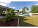 A spacious backyard features a well-maintained lawn, a pool, lush landscaping, and mature trees at 1060 Elkcam Blvd, Deltona, FL 32725