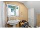 Small bathroom features a pedestal sink, storage cabinet, and a window with white curtains at 11200 Lane Park Rd, Tavares, FL 32778