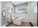Bright bathroom features a modern freestanding tub, beautiful windows, and tiled walls at 11200 Lane Park Rd, Tavares, FL 32778
