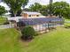 Beautiful backyard featuring a screened pool enclosure, meticulously kept lawn, and landscaping at 11200 Lane Park Rd, Tavares, FL 32778