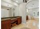 Bright, marble bathroom features dual sinks, granite countertops, glass enclosed shower, soaking tub and elegant chandelier lighting at 12614 Hawkstone Dr, Windermere, FL 34786