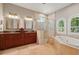 Bright, marble bathroom features dual sinks, granite countertops, glass enclosed shower, and soaking tub with arched windows at 12614 Hawkstone Dr, Windermere, FL 34786