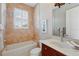 Bathroom featuring a single vanity, a tub with shower, natural lighting, and neutral tile throughout at 12614 Hawkstone Dr, Windermere, FL 34786
