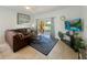 Comfortable living room with a brown couch, tile flooring, and sliding glass doors leading to outdoor patio at 130 Palermo St, Davenport, FL 33897