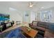 Open-concept living room with a large brown couch, tile flooring, and a view of the staircase and kitchen at 130 Palermo St, Davenport, FL 33897