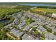 An aerial view showcases this townhouse community's mature landscaping, grey roofs, parking areas, and proximity to a pond and ball field at 131 Heritage Park St, Winter Springs, FL 32708