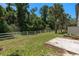 A spacious backyard with a white fence is bordered by lush green trees and plants at 131 Heritage Park St, Winter Springs, FL 32708