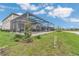 A covered screened-in pool area with patio furniture, overlooking a large backyard and pond at 13640 Haulover Beach Ln, Orlando, FL 32827