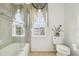 Bathroom featuring a tub and shower combination with glass enclosure, toilet, and natural light at 14819 Braywood Trl, Orlando, FL 32824