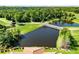 Aerial view of a pond with a bridge and lush green golf course surrounded by tall green trees at 1565 Corkery Ct, Winter Springs, FL 32708