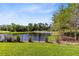 A well-kept lawn with black fence overlooks a tranquil pond and lush trees in the backyard at 1565 Corkery Ct, Winter Springs, FL 32708