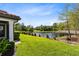 Backyard view of a well-maintained lawn, bordered by a black fence, with a pond and trees beyond at 1565 Corkery Ct, Winter Springs, FL 32708